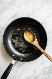 This image shows ghee being heated in a pan, getting ready for frying the dough balls to a deep golden brown.