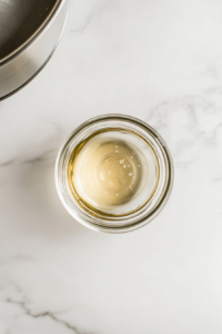 This image shows a person carefully checking a clear glass jar, ensuring it is clean and free from cracks before using it to store homemade sweet pickles.