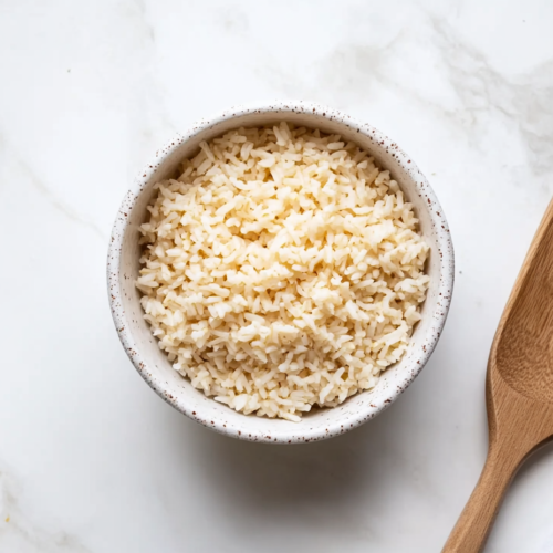 instant-pot-calrose-rice-served-in-a-white-bowl-with-a-wooden-spoon-on-the-side