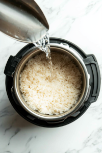 This image shows an Instant Pot filled with rinsed Calrose rice and water, prepared for cooking to achieve a fluffy and tender texture.