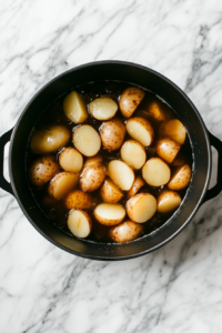 This image shows a large pot of water at a rolling boil with diced potatoes cooking inside, softening them for the creamy mashed potato base of Shepherd’s Pie Soup.