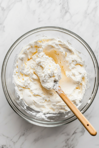 mixing-cream-cheese-sugar-and-vanilla-for-a-smooth-filling-in-a-glass-bowl