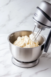 This image shows the dough hook in action, mixing the pizza dough ingredients on speed 2 for about one minute to combine them into a smooth mixture.