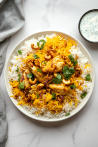 This image shows a generous serving of Chicken Dum Biryani plated with tender chicken pieces, fluffy saffron-kissed rice, and garnished with crispy onions, nuts, and fresh herbs for an irresistible final touch.