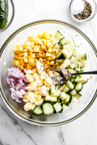 This image shows a generous amount of mayonnaise being poured into the Russian Crab Salad mixture, along with salt and pepper, enhancing the flavors and creating a rich, creamy texture.