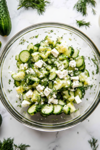 This image shows the completed cucumber feta salad, served immediately in a bowl, looking fresh and appetizing with its vibrant ingredients and tangy dressing.