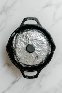 This image shows a heavy-bottomed biryani pot being sealed tightly with dough, locking in the steam and flavors for a traditional dum cooking method that results in perfectly cooked Chicken Dum Biryani.