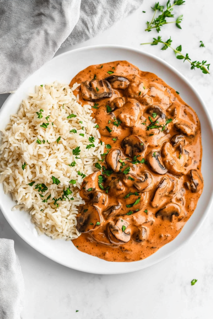 serving-creamy-vegan-mushroom-stroganoff-with-rice-and-cilantro-garnish-7650959-683x1024