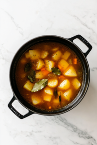 This image shows a large pot of Shepherd’s Pie Soup gently simmering on the stovetop, allowing the flavors of potatoes, vegetables, and seasonings to blend into a hearty and delicious dish.