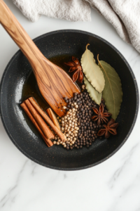 This image shows whole spices sizzling in hot oil, releasing their aromatic flavors to enhance the Mushroom Masala.