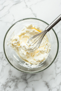 This image shows a mixing bowl with softened cream cheese being beaten until creamy and smooth, forming the base of the classic cheese ball.
