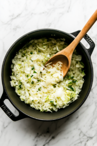 This image shows thinly sliced cabbage and onions sizzling in a pot as they soften and caramelize, building a rich flavor for the soup.