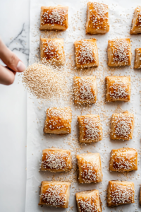 sprinkling-sesame-seeds-on-sausage-rolls-top-down-view