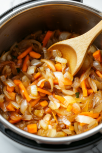 This image shows onions being sautéed in an Instant Pot until golden brown and caramelized, adding deep flavor to the dish.