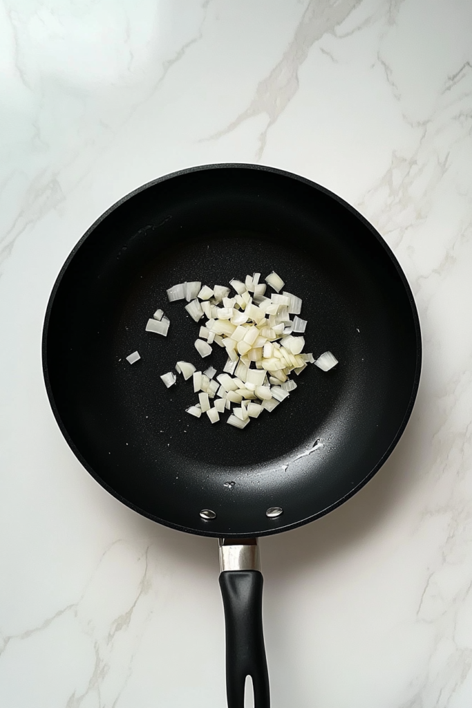 black-skillet-sauteing-onion-and-garlic-on-white-marble-countertop-9071466-683x1024