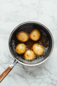 This image shows diced potatoes boiling in a pot, becoming tender for the perfect texture in No Onion Potato Salad.