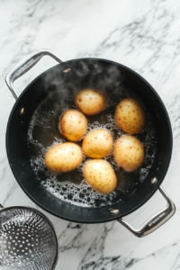 This image shows diced potatoes boiling in a pot, softening to the perfect texture for Olivye Ukrainian Potato Salad.