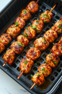 This image shows skewered Chicken Seekh Kababs sizzling in an air fryer, developing a beautifully charred exterior while staying juicy inside. The golden-brown crust adds a delicious smoky depth.