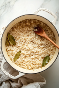 This image shows perfectly cooked basmati rice, each grain separate and fluffy. The delicate aroma of bay leaves and cloves infuses the rice, making it the perfect base for the layered Chicken 65 Biryani.