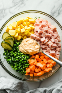 This image shows mayonnaise being stirred into the Olivye Ukrainian Potato Salad, coating each ingredient in a creamy, flavorful dressing.