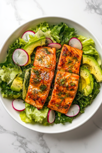 This image shows the finished avocado salmon salad plated in a white bowl, with a beautifully smoked salmon fillet on top, ready to serve.