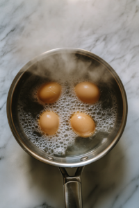 This image shows eggs boiling in a pot, followed by a cooling process to make peeling easier for the salad.