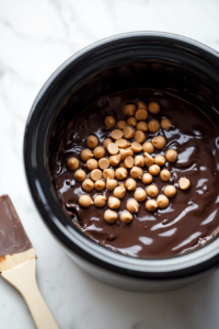melting-chocolate-peanut-butter-and-nuts-in-crock-pot-for-smooth-mixture-top-down-view