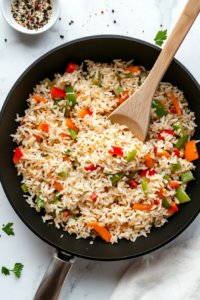 This image shows rice and a blend of seasonings being mixed into the sautéed vegetables and sausage, enhancing the flavor of the dish.
