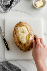 This image shows a freshly baked potato sliced open, revealing a fluffy, steamy center, ready to be fluffed and topped with butter.