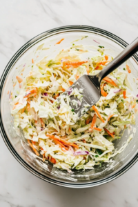 pouring-creamy-dressing-over-mixed-vegetables-to-coat-coleslaw-evenly