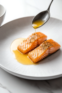 This image shows a rich lemon dill dressing being drizzled over a freshly cooked salmon fillet, adding a tangy and herby flavor.