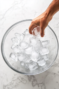 This image shows a large bowl filled with ice water, ready to be used for shocking the boiled potatoes to stop the cooking process.