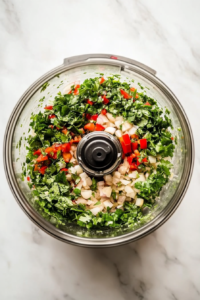 This image shows a food processor blending marinated chicken with a mix of aromatic spices, garlic, and herbs into a smooth yet textured kebab mixture, ensuring even seasoning in every bite.