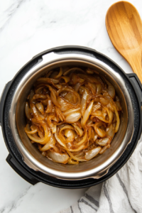 This image shows onions being sautéed in an Instant Pot until golden brown and caramelized, adding deep flavor to the dish.