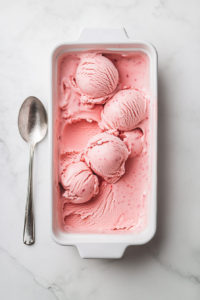: This image shows a top-down view of a freezer-safe container filled with freshly churned strawberry ice cream, ready to be frozen for the perfect consistency.