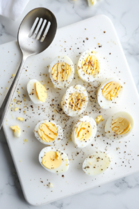 This image shows freshly boiled eggs being cooled, peeled, and chopped into small pieces on a wooden cutting board in preparation for egg salad.