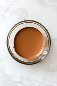 adding-shortening-to-melted-chocolate-in-glass-bowl-white-marble