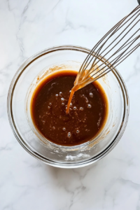 This image shows vanilla extract being stirred into the brownie batter for added depth and aroma.