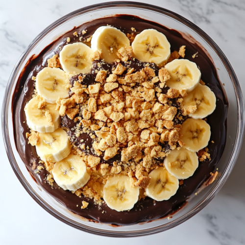 banana-chocolate-trifle-in-a-glass-bowl-layered-with-crushed-graham-crackers-rich-chocolate-ganache-and-sliced-bananas