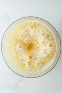 The pina colada mixture in the blender is being blended into a creamy, frothy consistency, ready to pour.