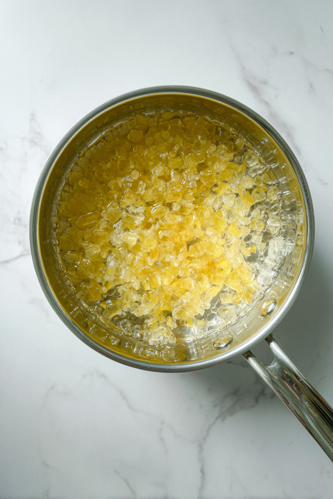boiling-lemon-syrup-mixture-in-glass-saucepan-on-marble