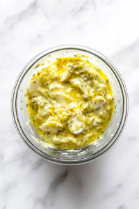 This image shows a ceramic bowl of egg salad placed inside a refrigerator shelf, allowing the flavors to deepen and the salad to chill before serving.