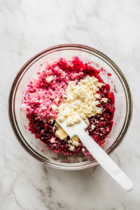 This image shows the cranberry jalapeño dip being mixed to a smooth and spreadable consistency, with creamy swirls blending into a luscious texture.
