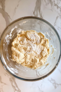 This image shows smooth dough placed in a greased glass bowl, covered and rising in a warm spot.