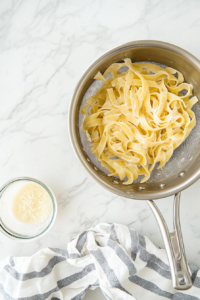 This image shows pumpkin purée and cream being stirred together in a pan, forming a smooth and velvety sauce.