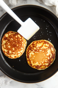 This image shows a pancake being flipped to cook the second side until it's beautifully golden brown.