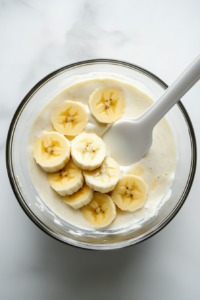glass-bowl-filled-with-chopped-bananas-and-a-generous-layer-of-smooth-vanilla-cream