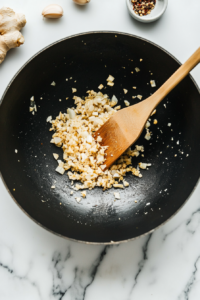 This image shows vibrant carrots being combined with olive oil, honey, salt, and pepper in a mixing bowl for a sweet and savory glaze.
