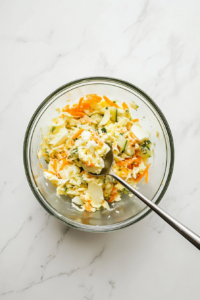 This image shows a bowl of egg salad being stirred until perfectly smooth, the creamy texture blending beautifully as the ingredients come together.