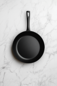 This image shows a nonstick pan being lightly oiled and heated over medium-high heat in preparation for cooking pancakes.